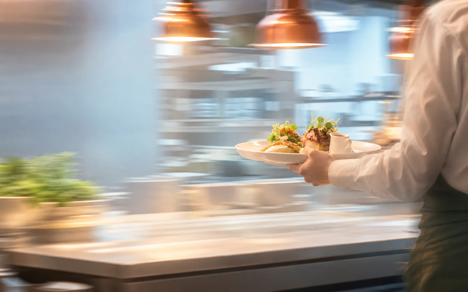 Restaurant team moving plated dishes across the pass during service